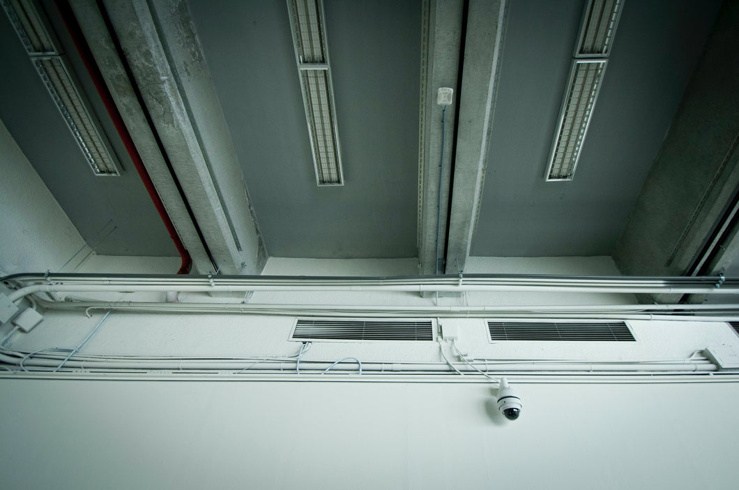Industrial ceiling with pipes, vents, and security camera